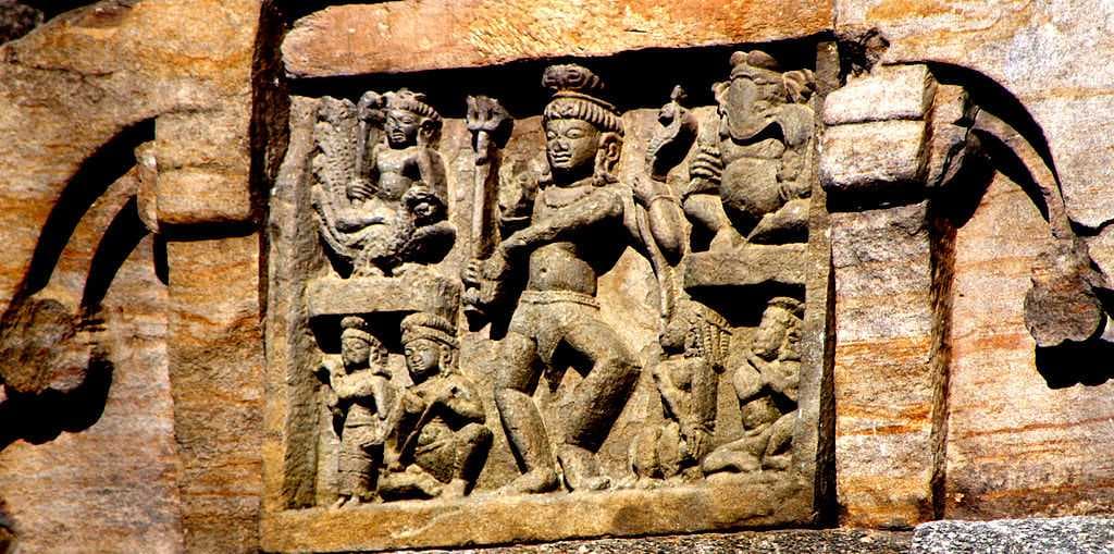 7th-century Nataraja relief on Temple 1; Ganesha in upper right corner, Skanda-Kartikeya on his peacock in upper left, Parvati in lower left and a musician playing vadya in lower right.[11]