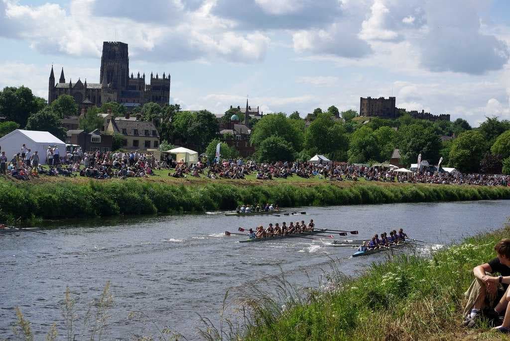 Durham Cathedral and Durham Castle as seen from the river bank whilst a boat race takes place between University College, Durham and Newcastle University