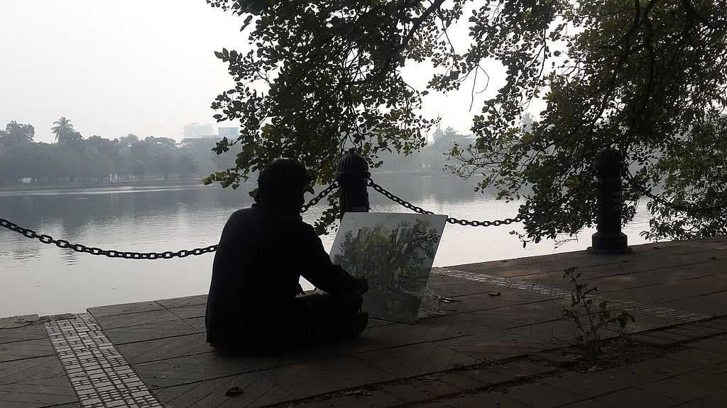 An artist draws a tree in front of the lake