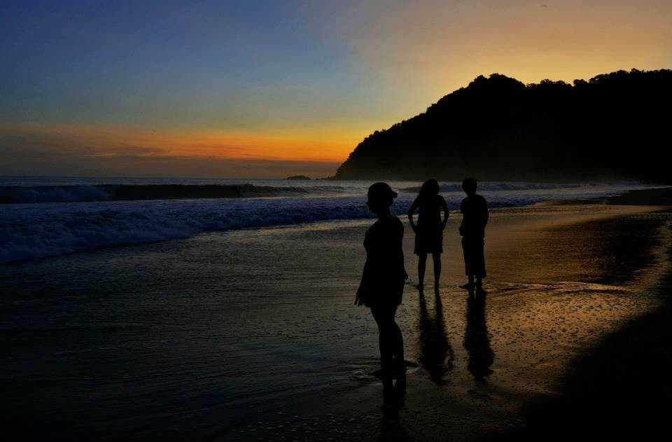 Tourists enjoying the beautiful sunset at Sukamade Beach in Banyuwangi, Indonesia
