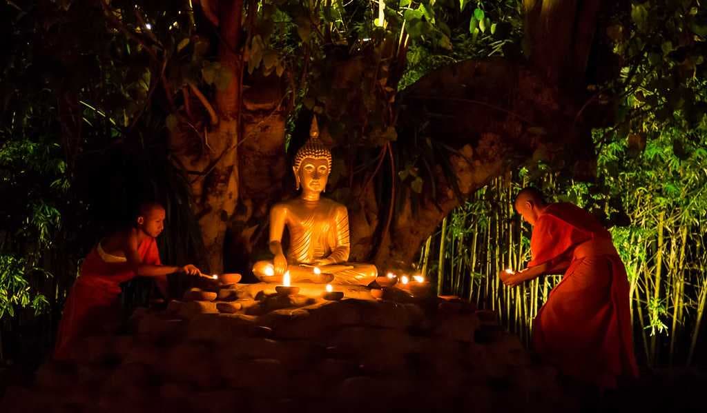 Monks lighting candles at Wat Phan Tao on Makha Bucha Day
