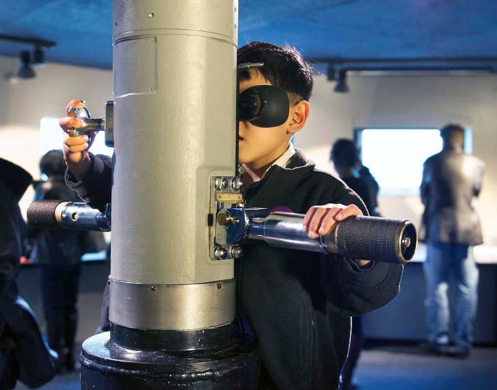 A young visitor looks through the WWII-era TANG periscope in MOHAI's Maritime Gallery