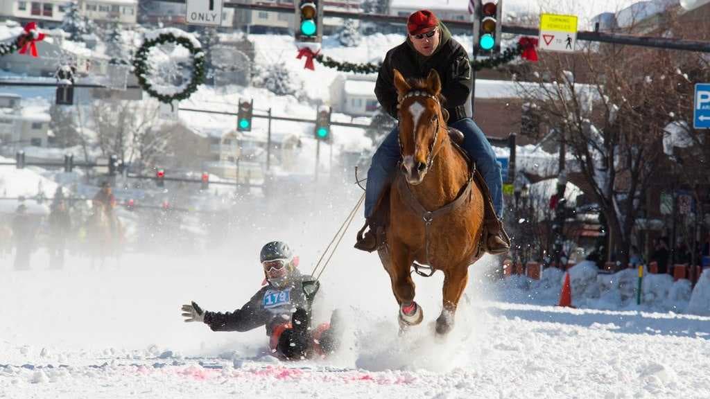 A kid sledding behind a horse down Main Street during Winter Carnival in Steamboat Springs