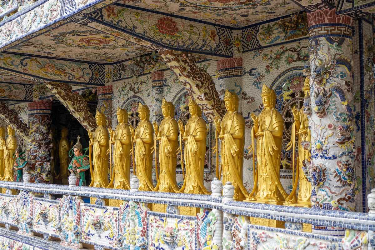 Many Golden Lady Buddha Statues in front of a Mosaic Wall at Linh Phuoc Pagoda